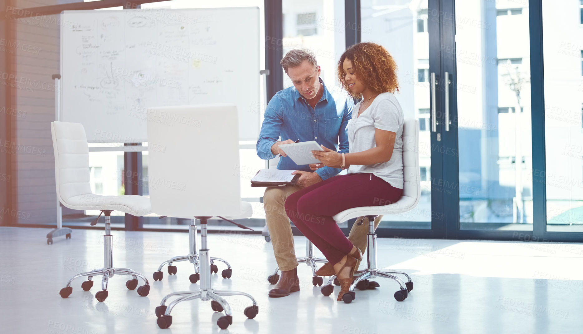 Buy stock photo Shot of two colleagues using a digital tablet together in a modern office