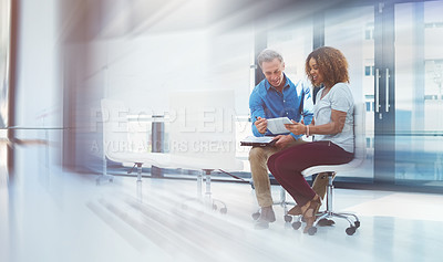 Buy stock photo Blurred motion shot of two colleagues using a digital tablet together in a modern office