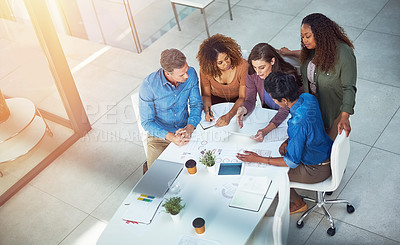Buy stock photo Shot of a group of designers gathering around a woman using a tablet in a meeting