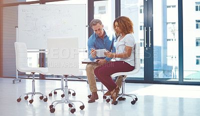 Buy stock photo Shot of two colleagues using a digital tablet together in a modern office