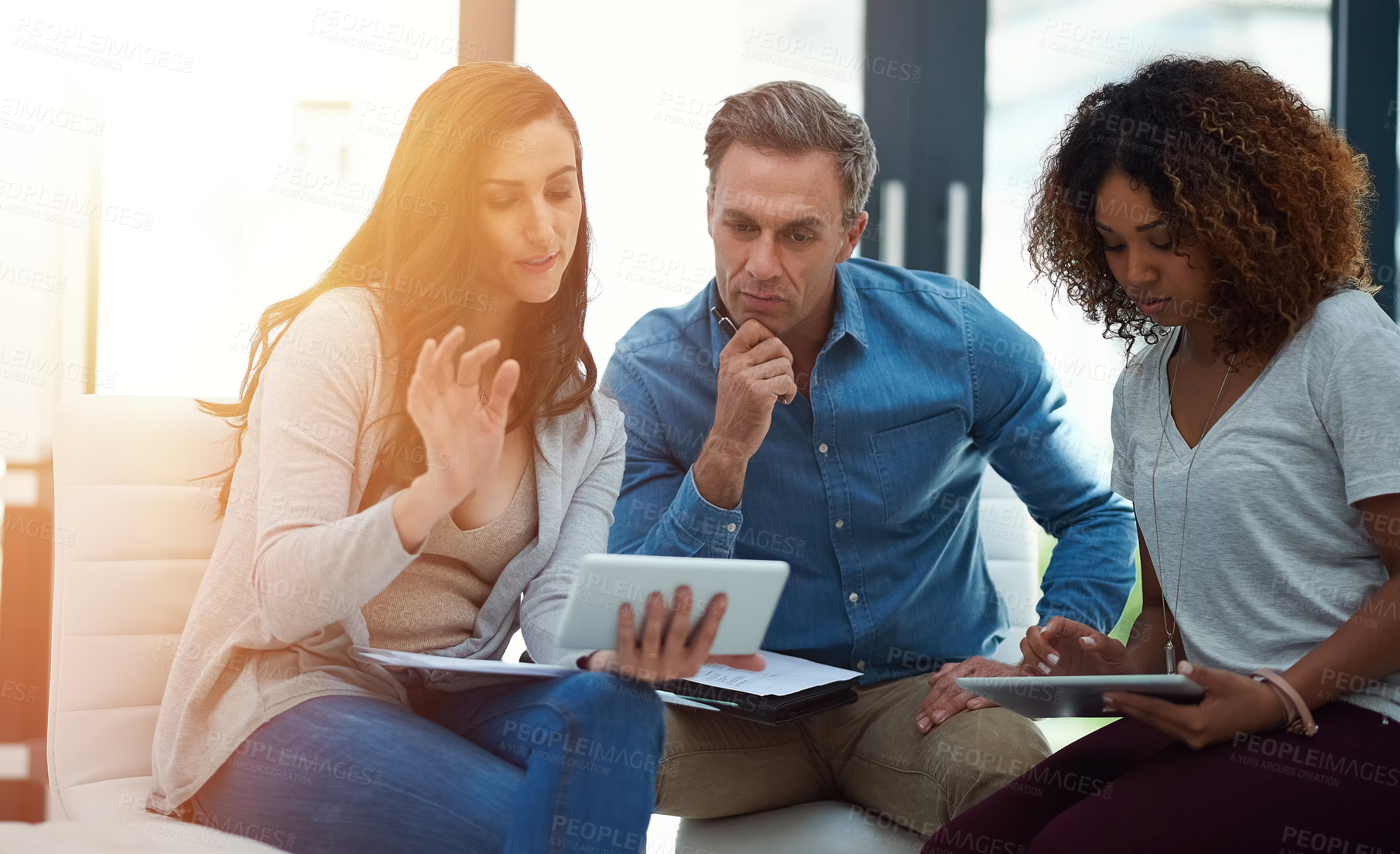 Buy stock photo Shot of a creative team using a digital tablet together during a meeting at work