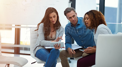 Buy stock photo Shot of a creative team using a digital tablet together during a meeting at work