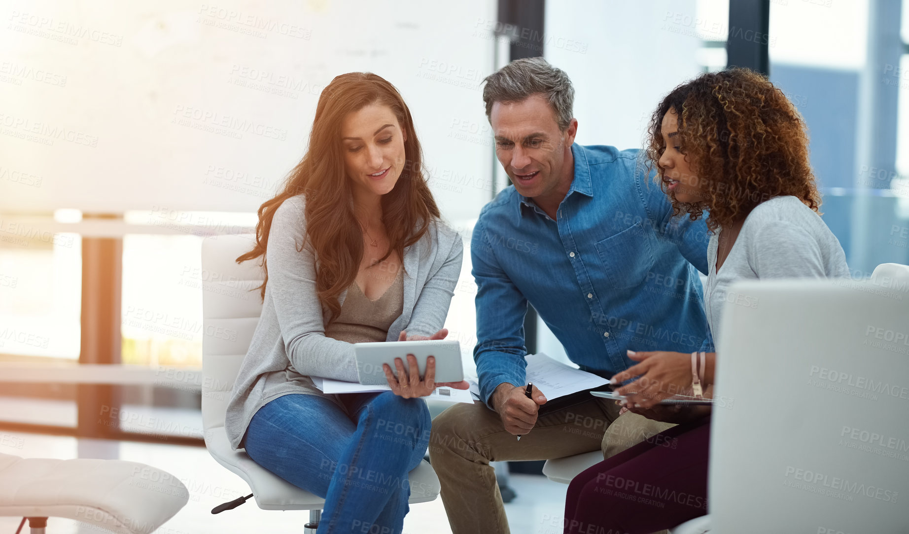 Buy stock photo Shot of a creative team using a digital tablet together during a meeting at work