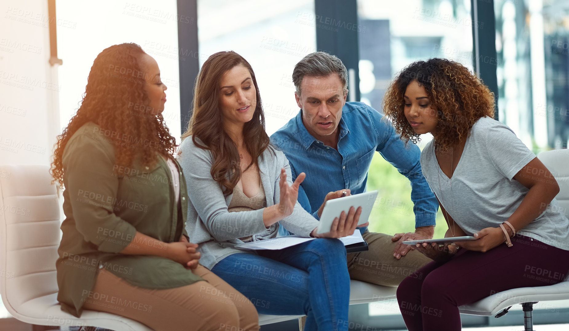 Buy stock photo Shot of a creative team using a digital tablet together during a meeting at work