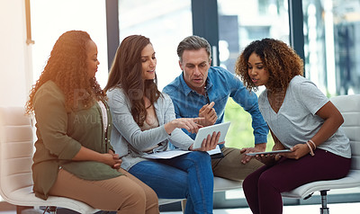 Buy stock photo Shot of a creative team using a digital tablet together during a meeting at work