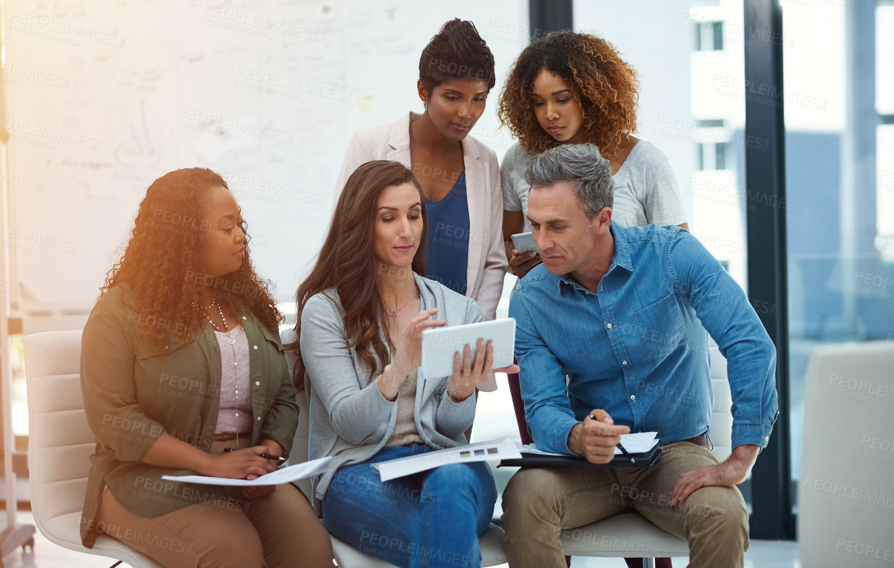 Buy stock photo Shot of a creative team using a digital tablet together during a meeting at work