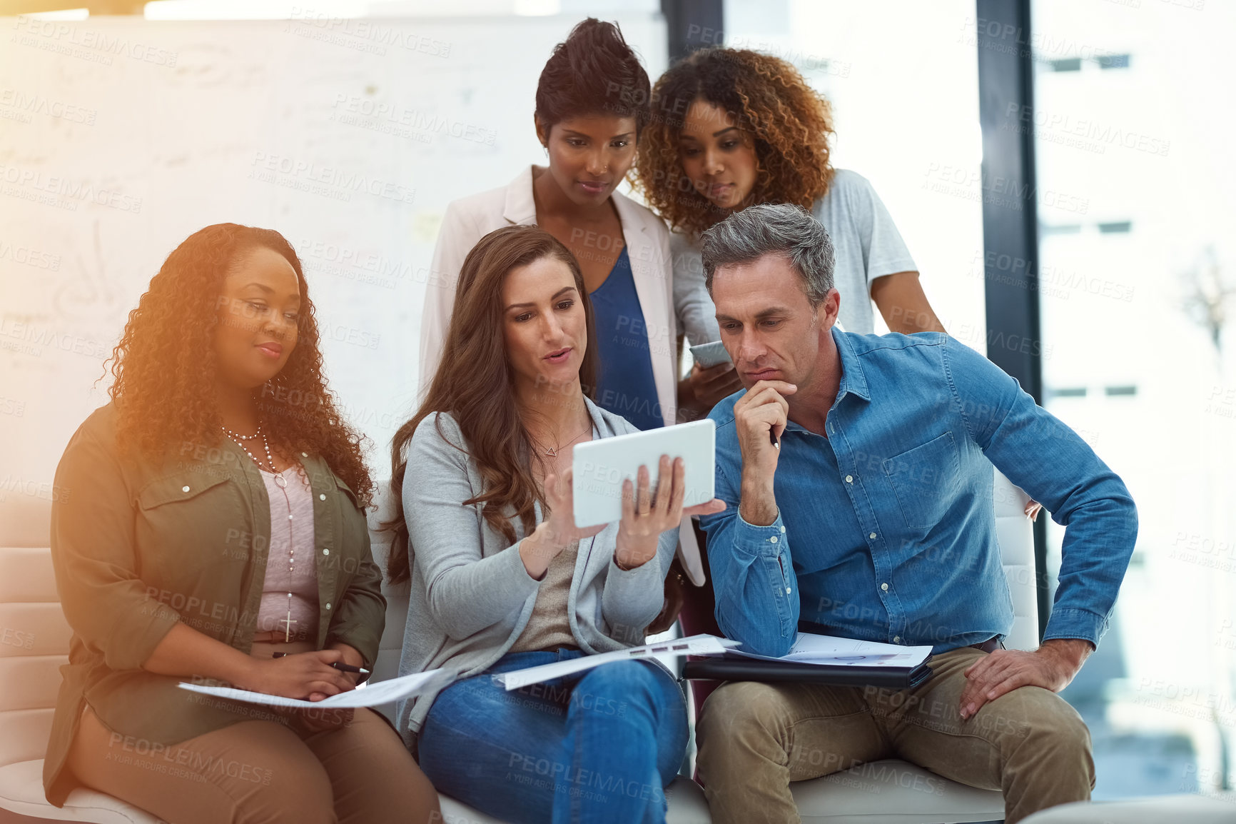 Buy stock photo Shot of a creative team using a digital tablet together during a meeting at work