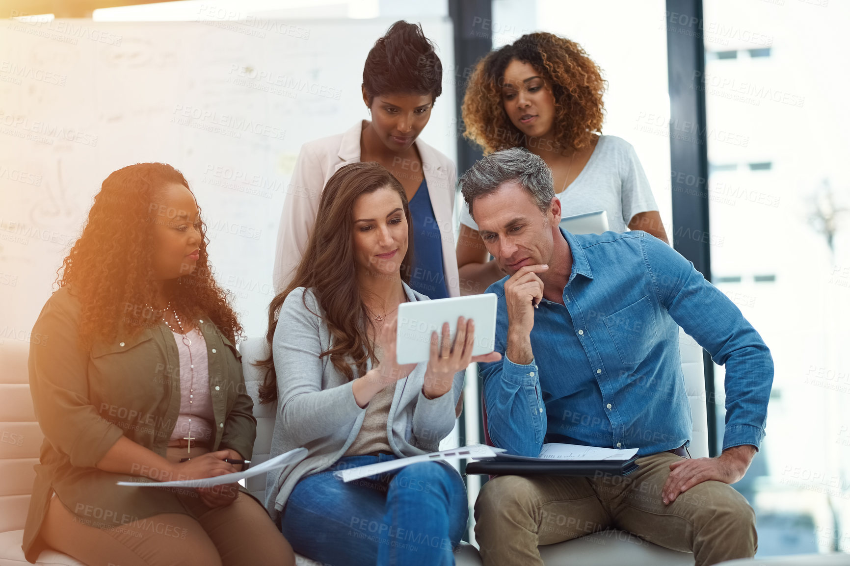 Buy stock photo Shot of a creative team using a digital tablet together during a meeting at work