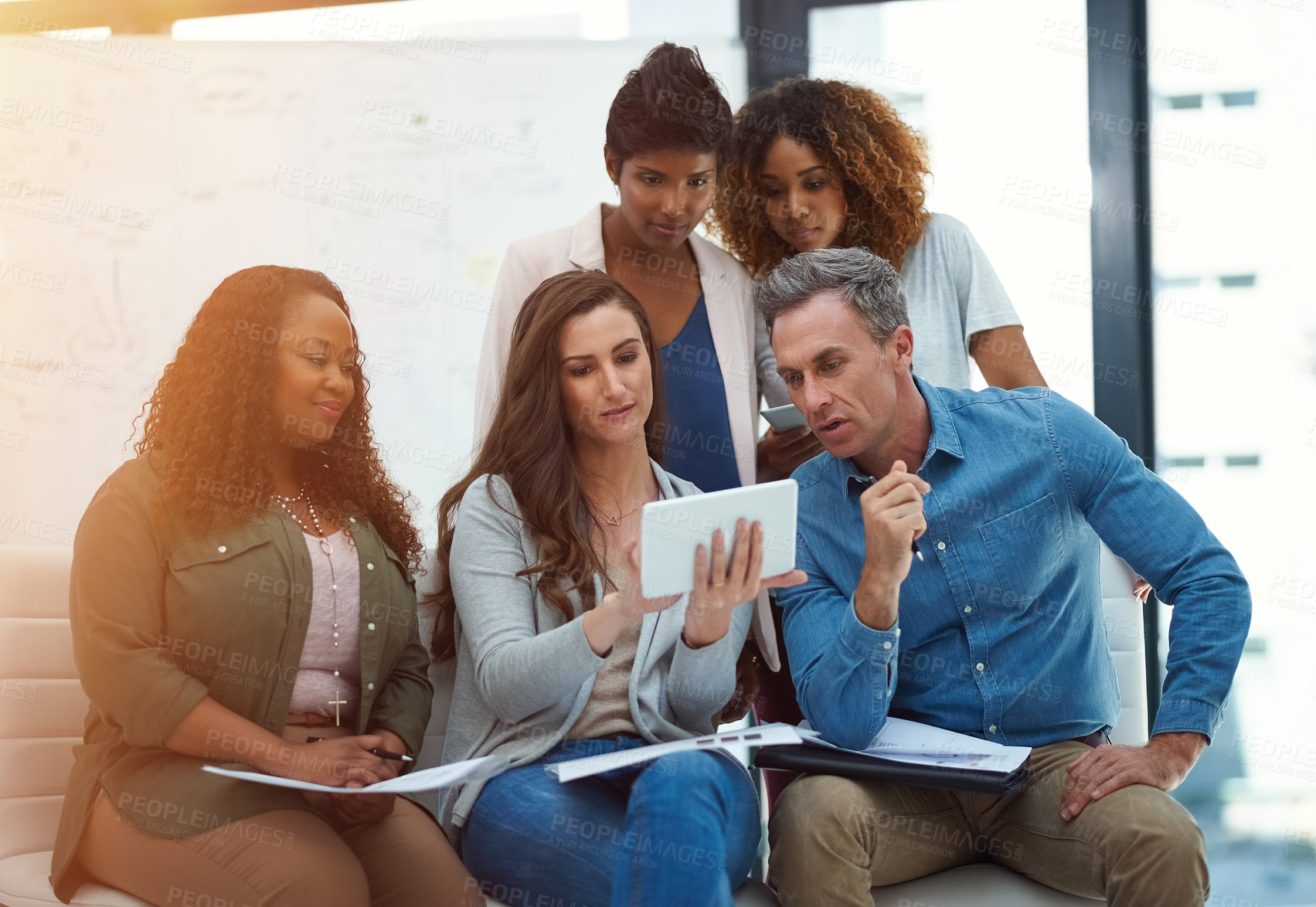 Buy stock photo Shot of a creative team using a digital tablet together during a meeting at work