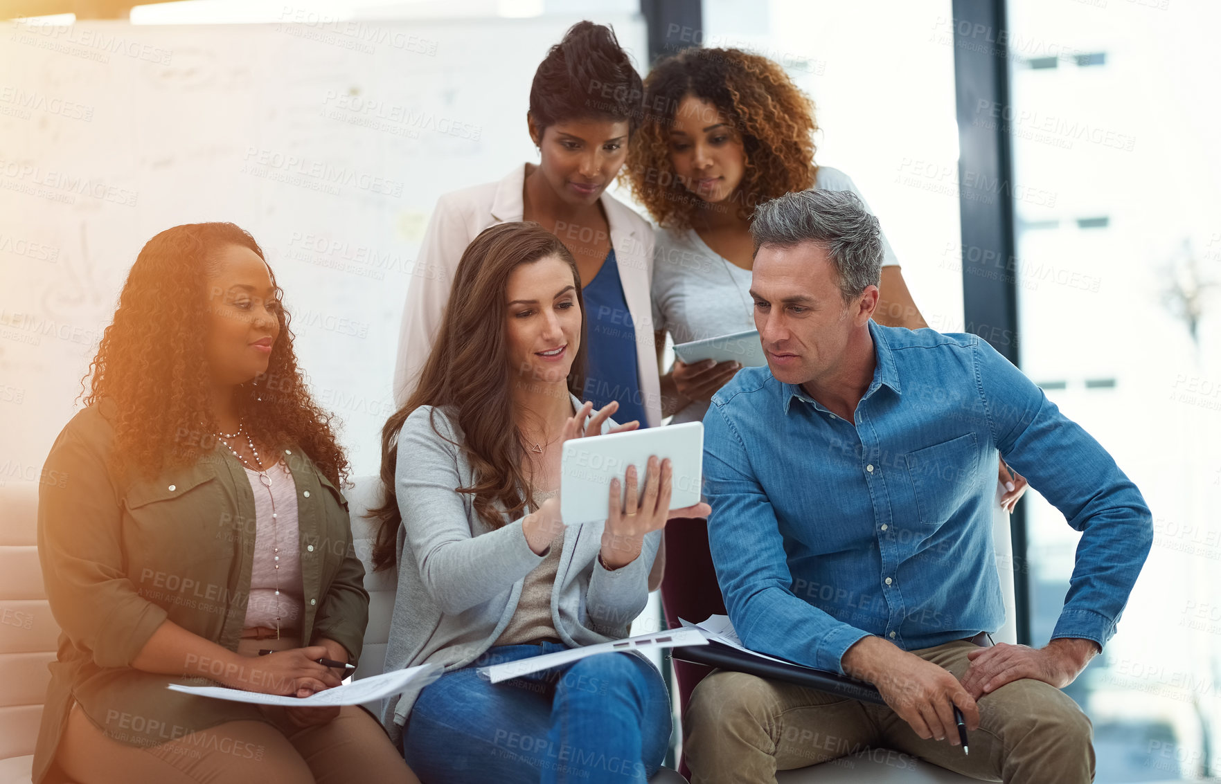 Buy stock photo Shot of a creative team using a digital tablet together during a meeting at work