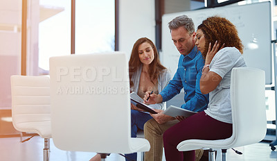 Buy stock photo Shot of a creative team using a digital tablet together during a meeting at work