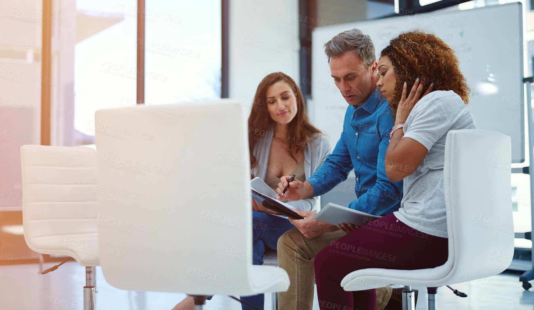 Buy stock photo Shot of a creative team using a digital tablet together during a meeting at work