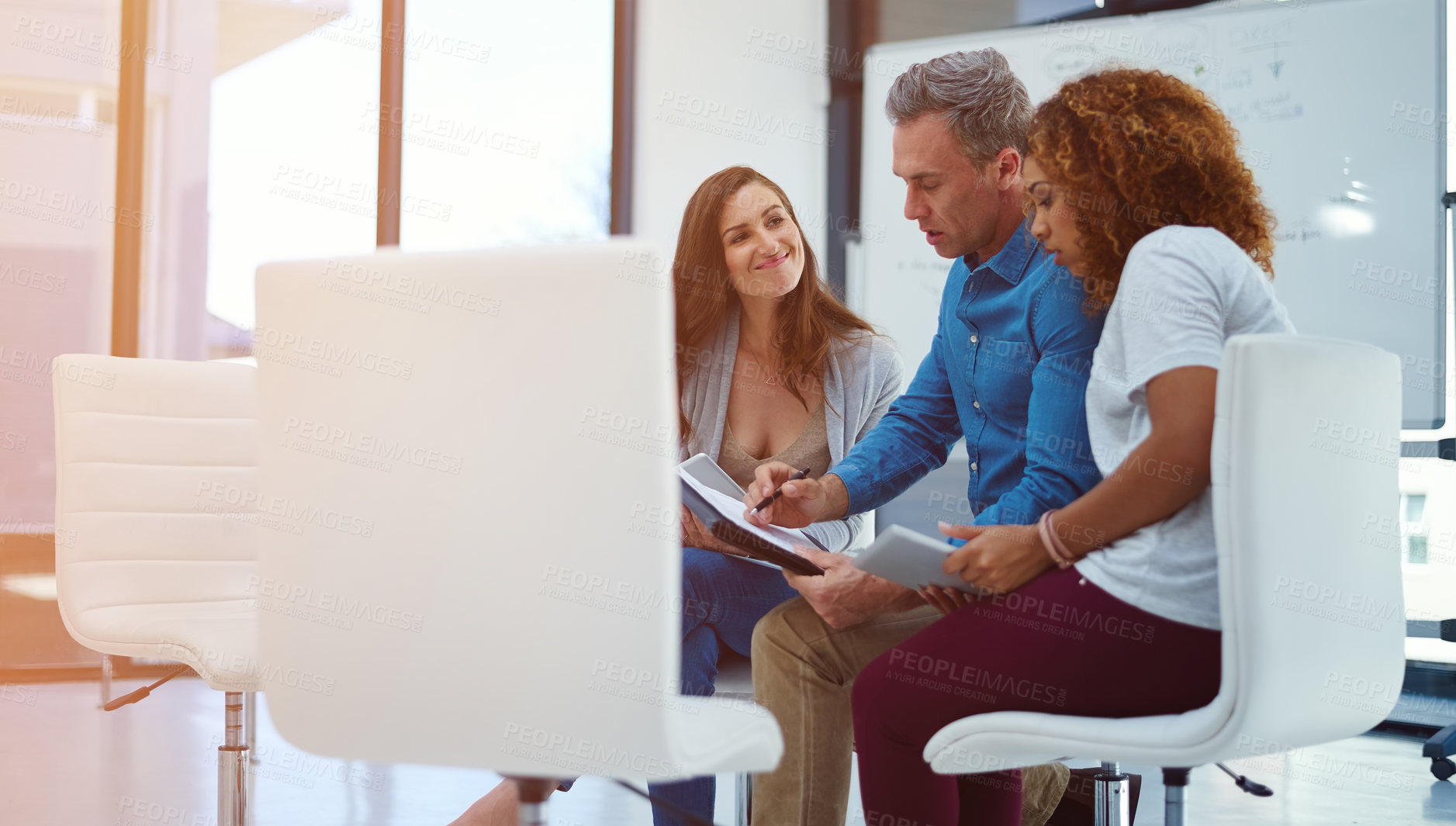 Buy stock photo Shot of a creative team using a digital tablet together during a meeting at work