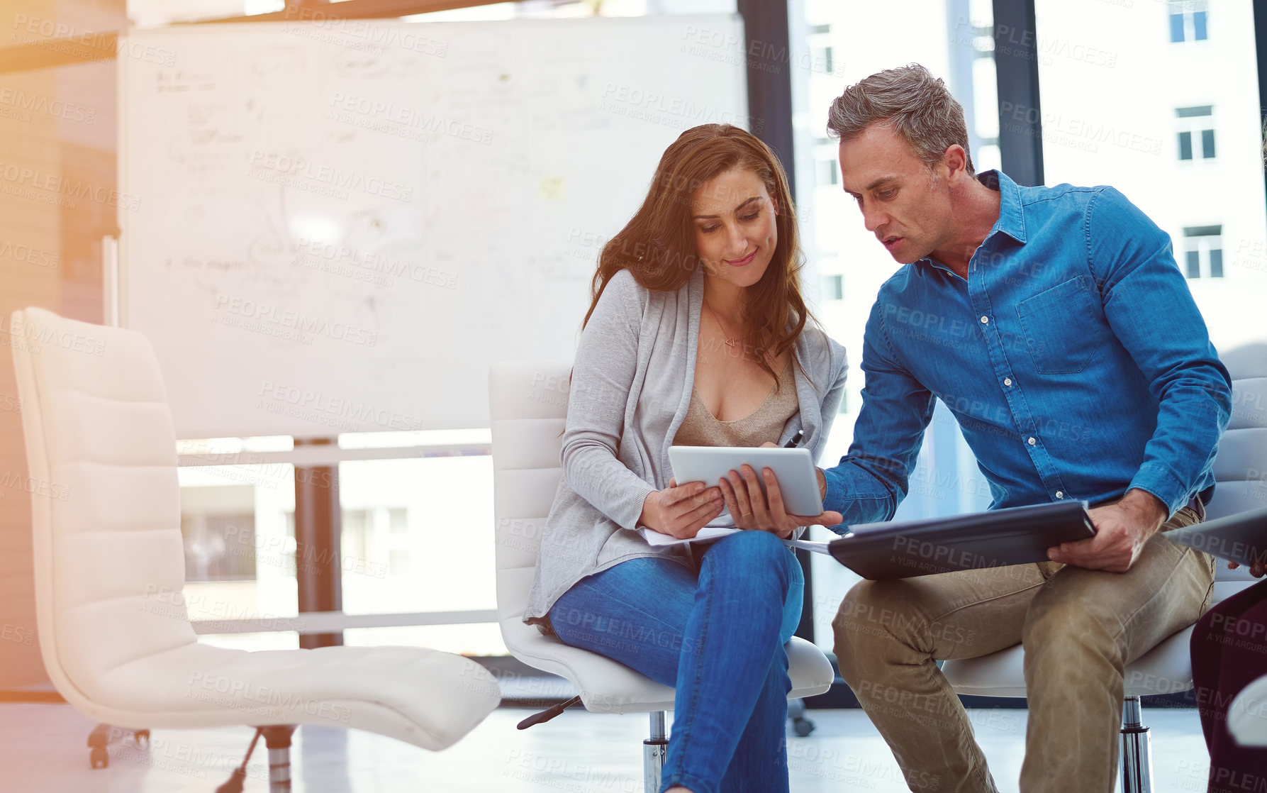 Buy stock photo Shot of two colleagues using a digital tablet together in a modern office