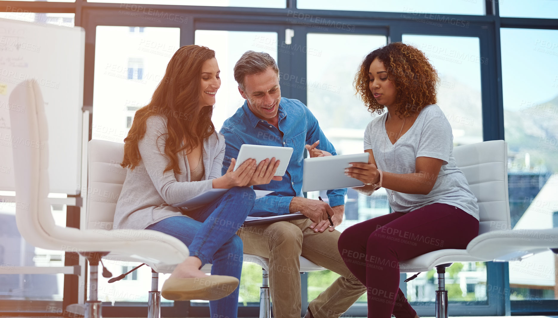 Buy stock photo Shot of a creative team using a digital tablet together during a meeting at work