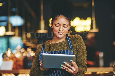 Buy stock photo Shot of a young woman using a digital tablet while working at a coffee shop