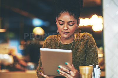 Buy stock photo Shot of a young woman using a digital tablet at a coffee shop