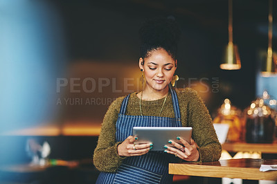 Buy stock photo Shot of a young woman using a  digital tablet while working at a coffee shop