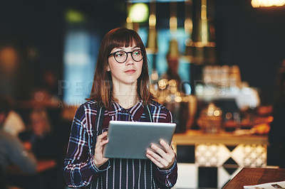 Buy stock photo Shot of a young woman using a  digital tablet while working at a coffee shop
