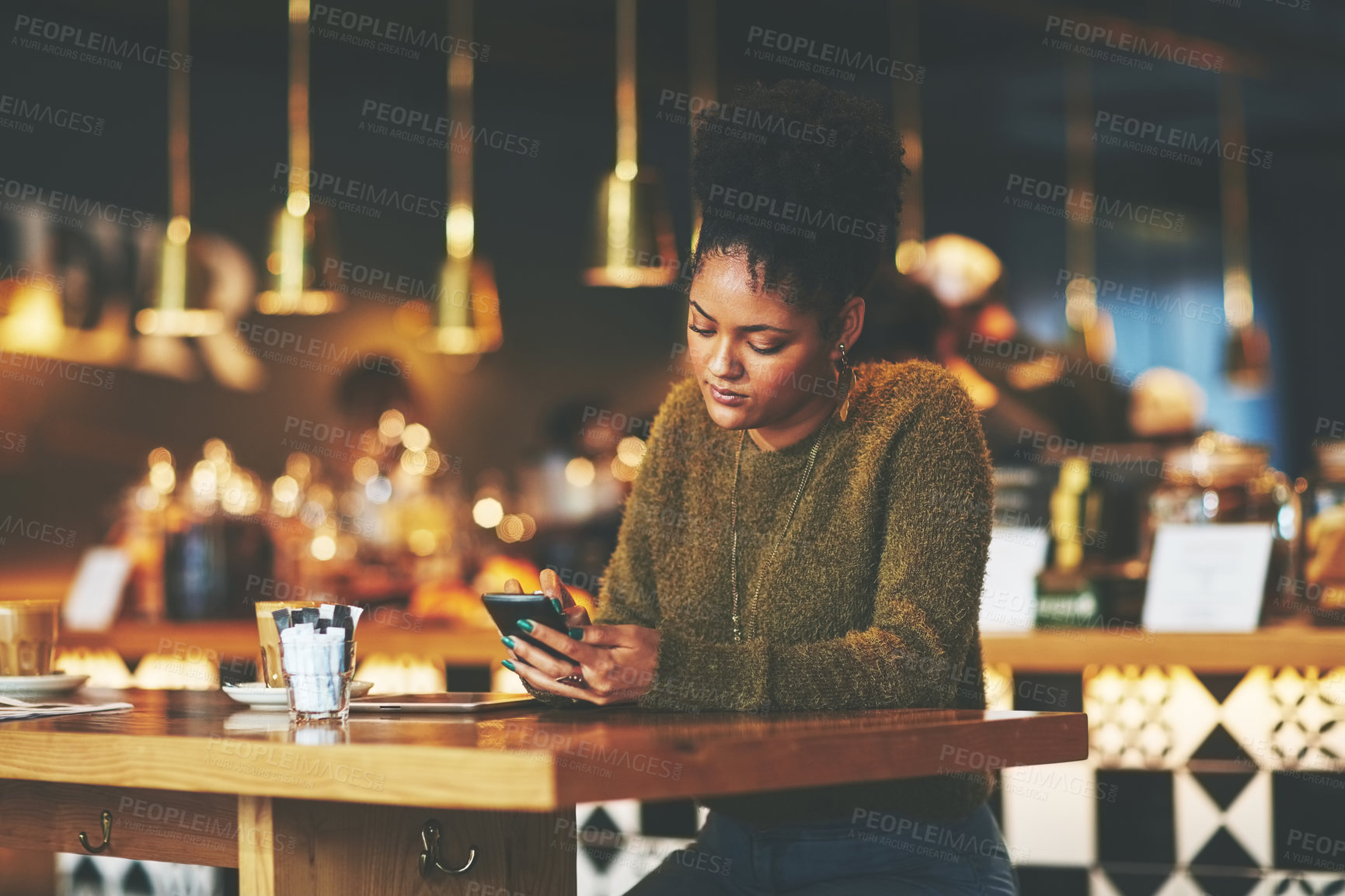 Buy stock photo Shot of a young woman using a mobile phone at a coffee shop