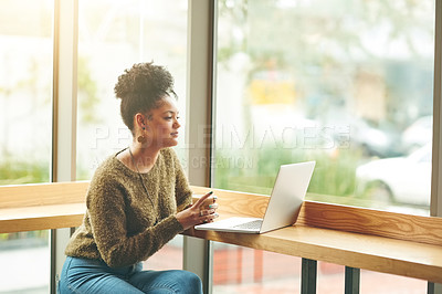 Buy stock photo Cropped shot of an attractive young woman looking thoughtful while using her laptop in a cafe