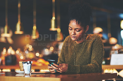 Buy stock photo Shot of a young woman using a mobile phone at a coffee shop
