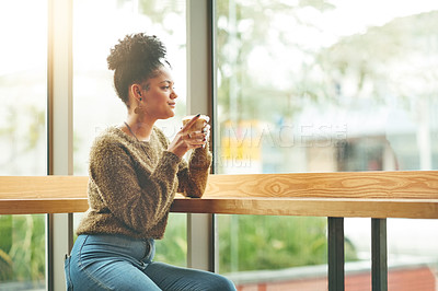 Buy stock photo Cropped shot of an attractive young woman looking thoughtful while enjoying a cup of coffee in a cafe