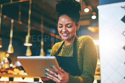 Buy stock photo Shot of a young woman using a  digital tablet while working at a coffee shop