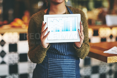Buy stock photo Shot of a woman holding a digital tablet with a graph on the screen at a coffee shop