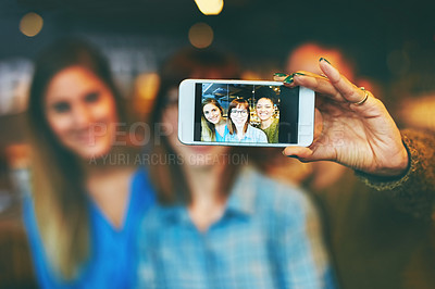 Buy stock photo Shot of three young friends taking a selfie together in a cafe
