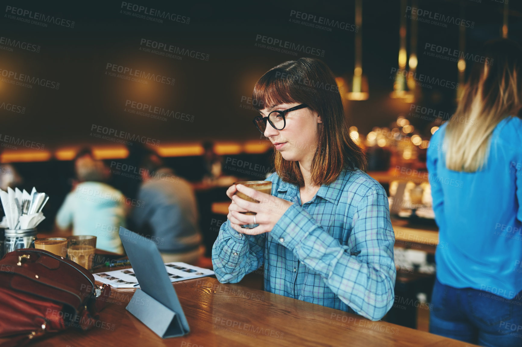 Buy stock photo Shot of an attractive young woman using a digital tablet in a cafe