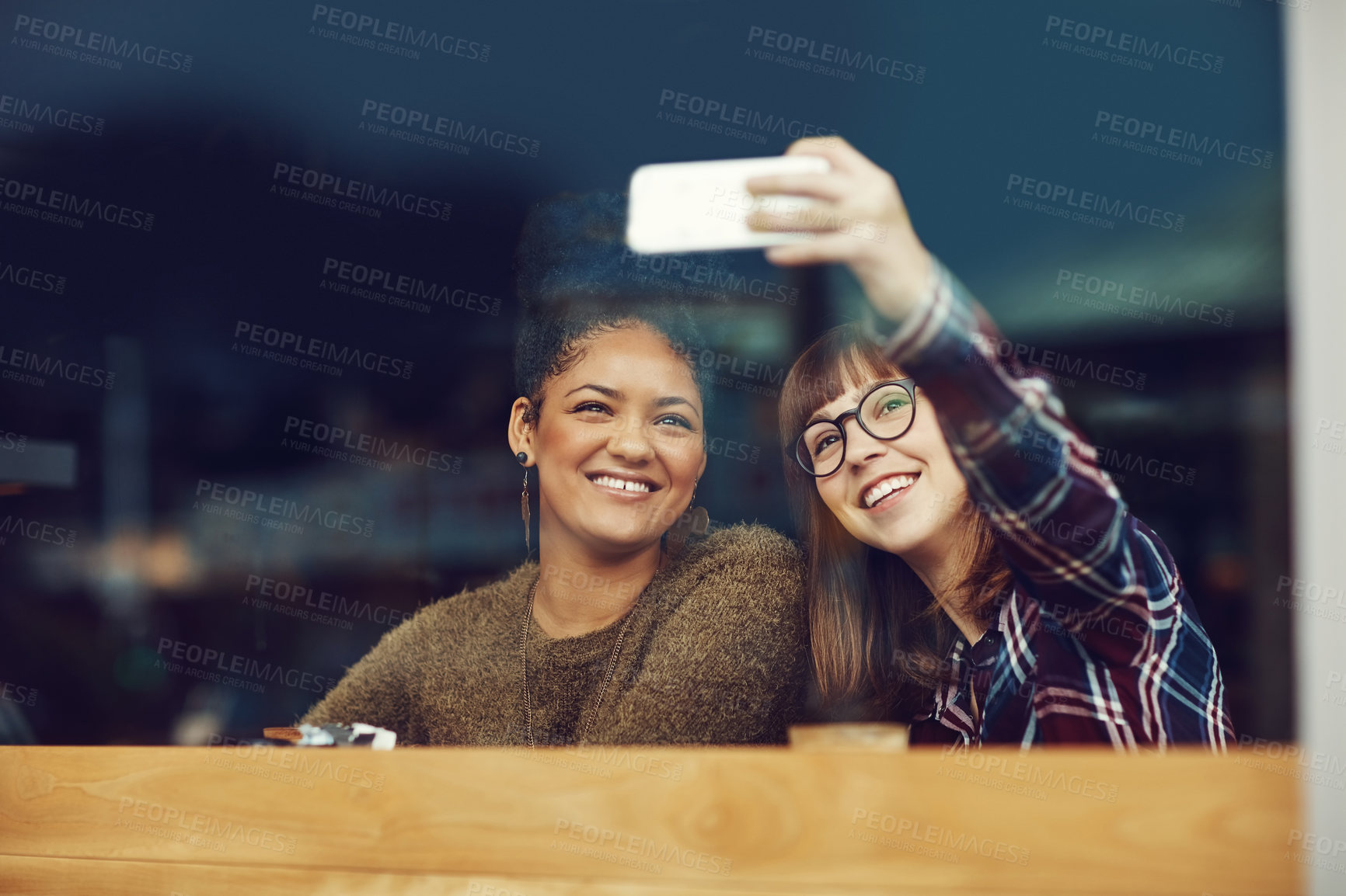 Buy stock photo Cropped shot of two young friends taking a selfie together in a cafe