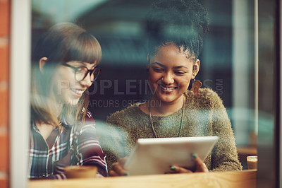 Buy stock photo Cropped shot of two young friends looking at something on a digital tablet in a cafe