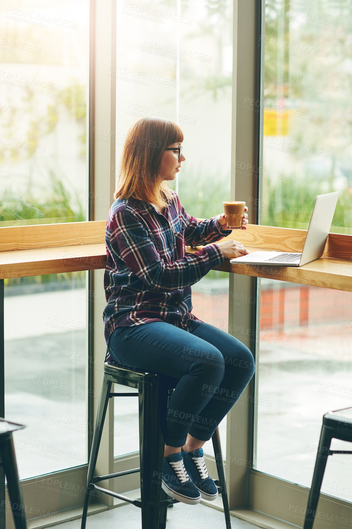 Buy stock photo Shot of an attractive young woman using her laptop in a cafe