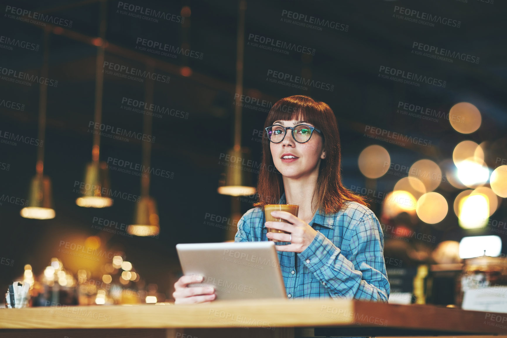 Buy stock photo Shot of an attractive young woman looking thoughtful while using a digital tablet in a cafe