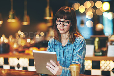 Buy stock photo Shot of an attractive young woman using a digital tablet in a cafe
