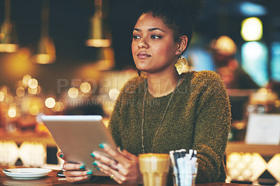 Buy stock photo Shot of an attractive young woman looking thoughtful while using a digital tablet in a cafe