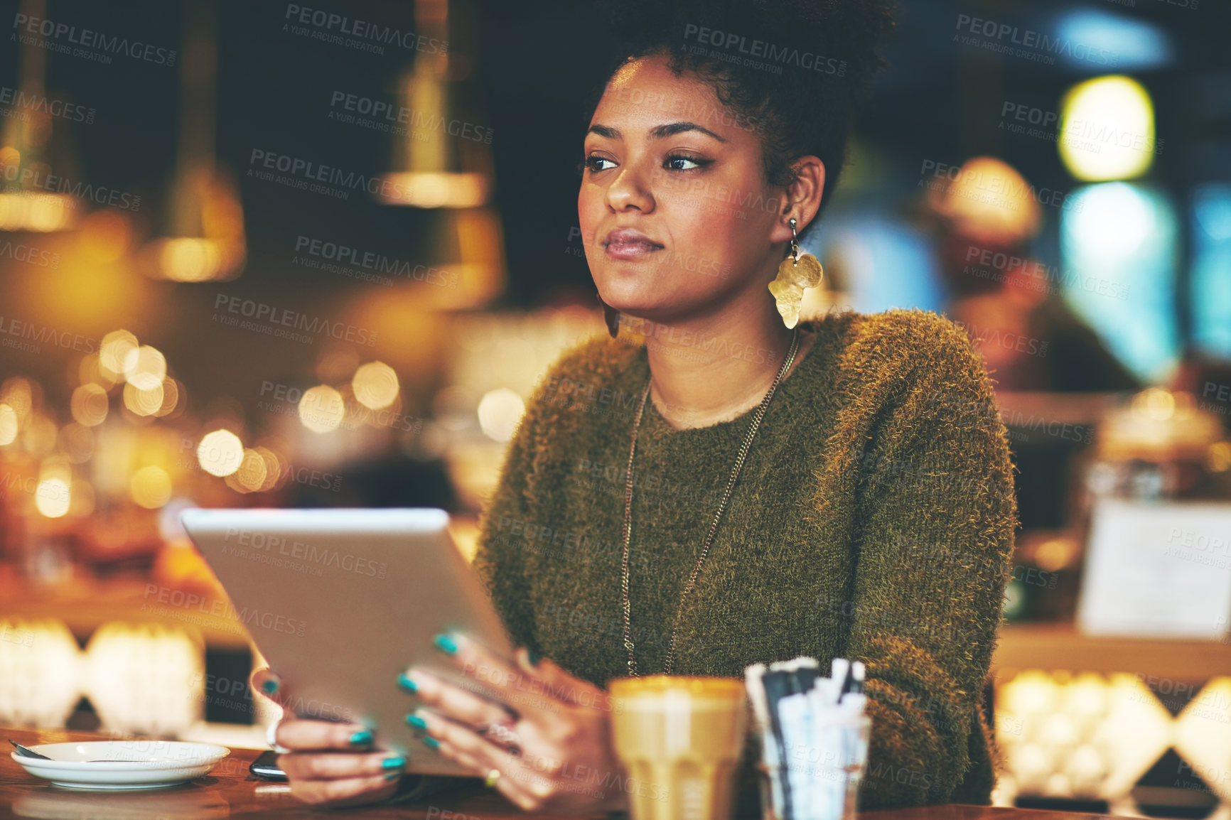 Buy stock photo Shot of an attractive young woman looking thoughtful while using a digital tablet in a cafe