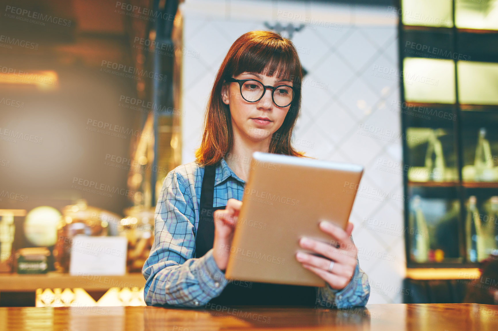 Buy stock photo Shot of a young business owner using a digital tablet in her cafe