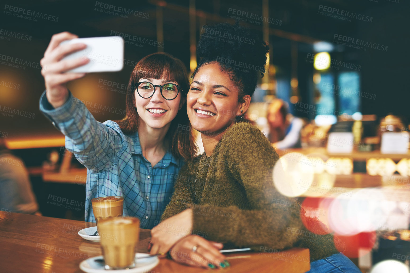 Buy stock photo Shot of two young friends taking a selfie together in a cafe