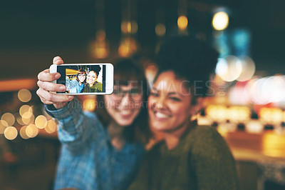 Buy stock photo Shot of two young friends taking a selfie together in a cafe