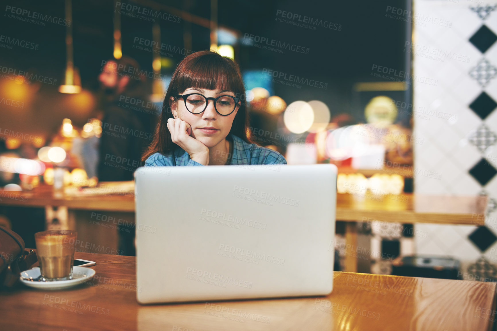 Buy stock photo Shot of an attractive young woman looking thoughtful while using her laptop in a cafe