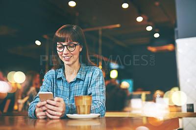 Buy stock photo Shot of an attractive young woman texting on her cellphone in a cafe