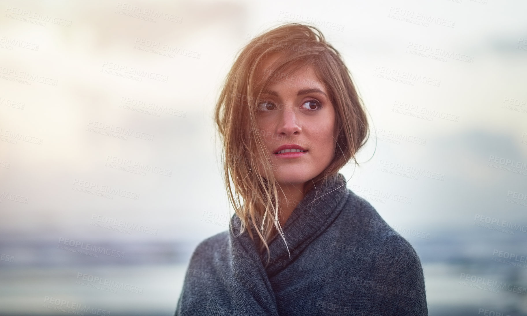 Buy stock photo Shot of an attractive young woman wrapped in a blanket on the beach