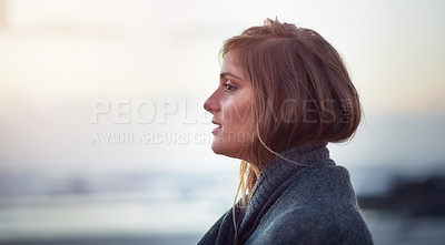 Buy stock photo Shot of an attractive young woman wrapped in a blanket on the beach