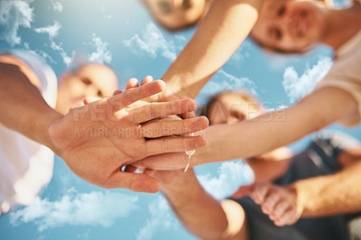 Buy stock photo Low angle shot of a group of young joining their hands together in solidarity