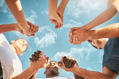 Buy stock photo Low angle shot of a group of young friends holding hands