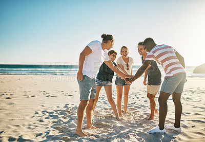 Buy stock photo Shot of a group of young joining their hands together in solidarity at the beach