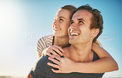 Buy stock photo Shot of a happy young couple enjoying a piggyback ride outdoors
