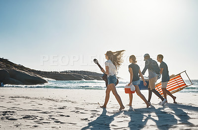 Buy stock photo Shot of a group of young friends walking on the beach on a sunny day